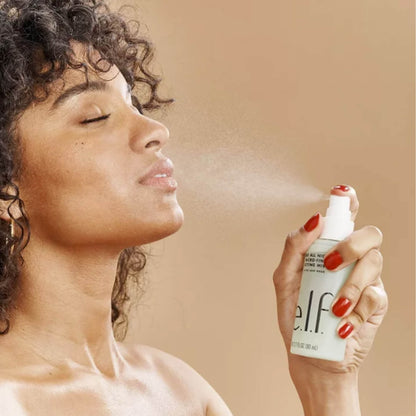 Woman using a 'elf' spray bottle on her face against a beige background in Pakistan