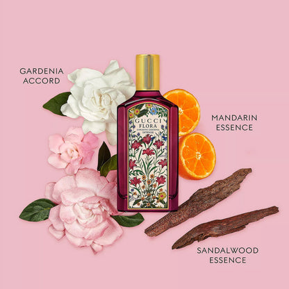 Gucci Flora perfume bottle with flowers, oranges, and sandalwood on a pink background