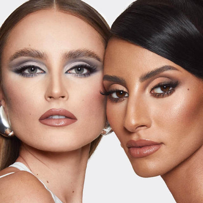 Two women with makeup close to each other on a plain background