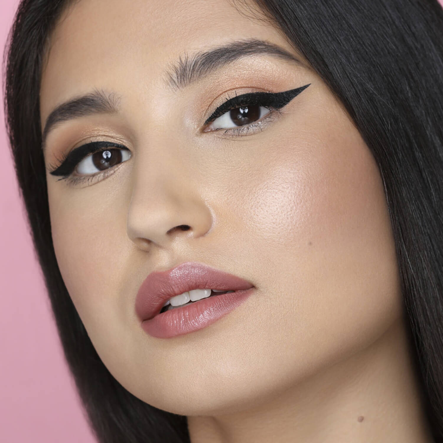 Close-up of a woman with cat-eye makeup on a pink background