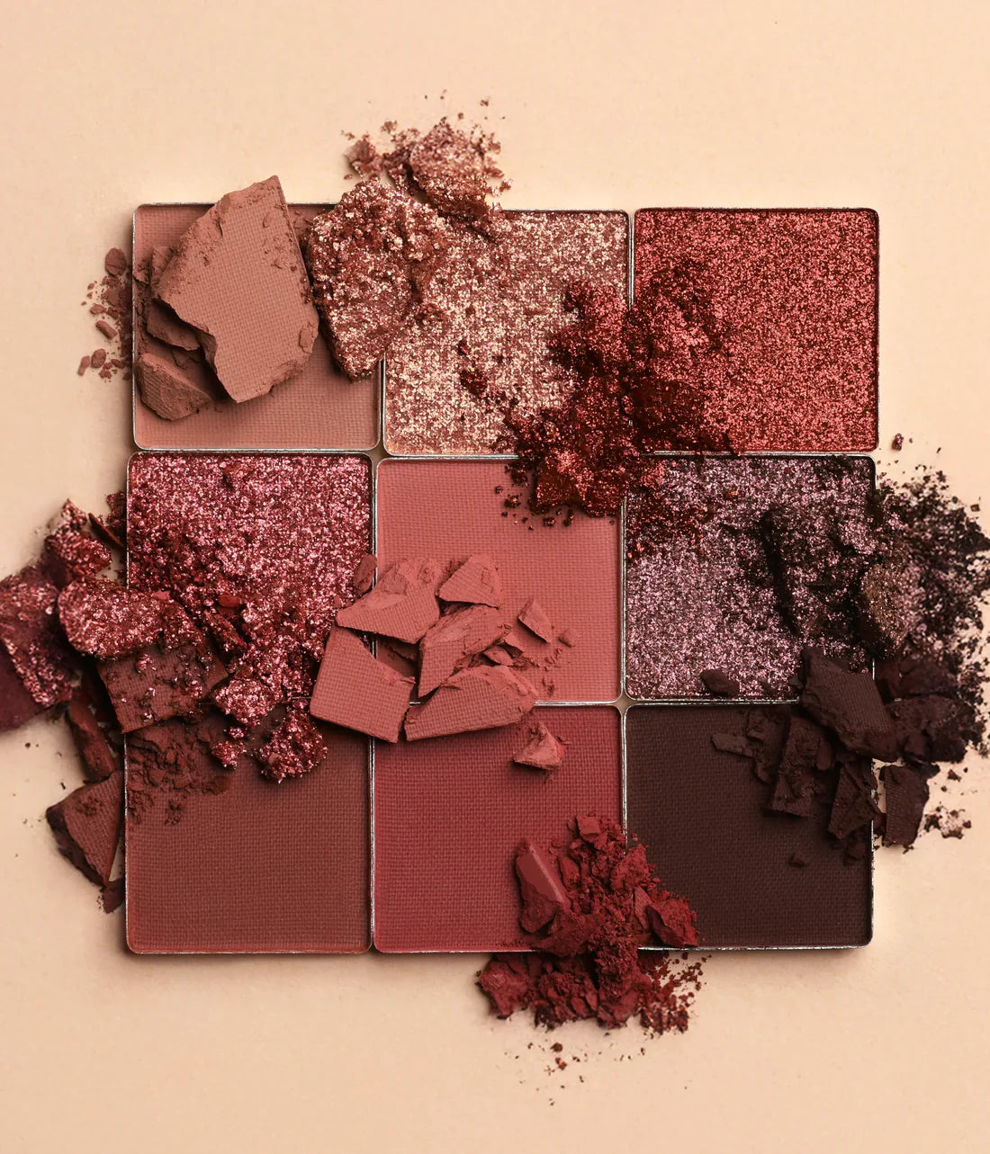 Makeup palette with crushed eyeshadow shades on a beige background