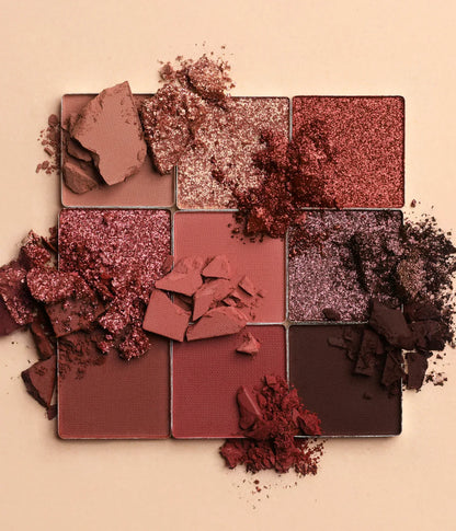 Makeup palette with crushed eyeshadow shades on a beige background