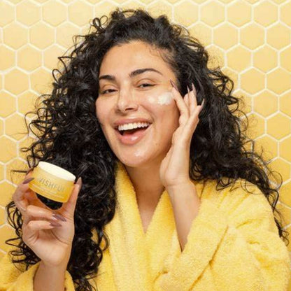 Woman applying cream to her face with a yellow background