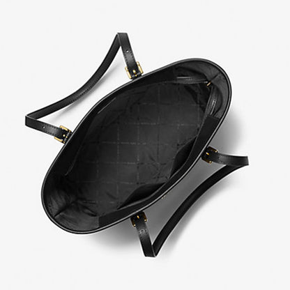 Black michael kors handbag with gold hardware on a light gray background