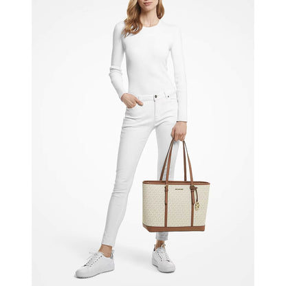 A model holds a Michael Kors tote bag with a beige monogram pattern and brown leather trim available at Heygirl.pk in Pakistan