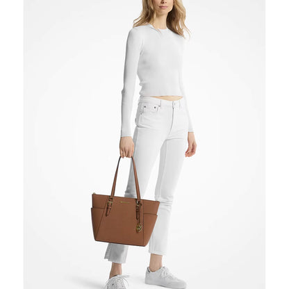 A model holds a brown Michael kors leather tote bag with gold-tone hardware against a plain white studio background.
