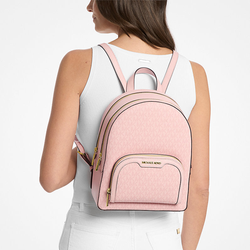A girl wearing a pink michael kors backpack on a white background