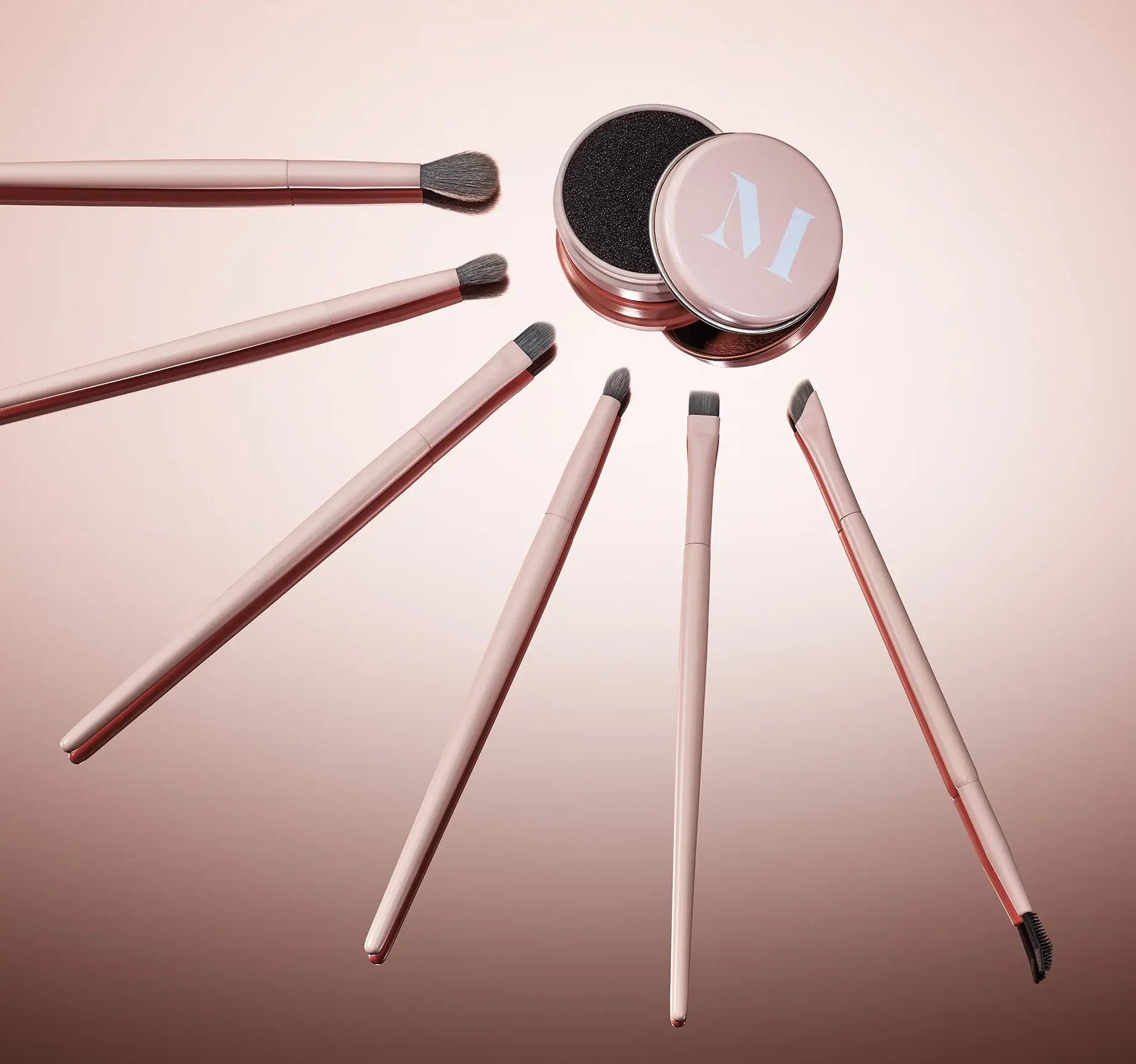 Set of makeup brushes with a pink container on a gradient background