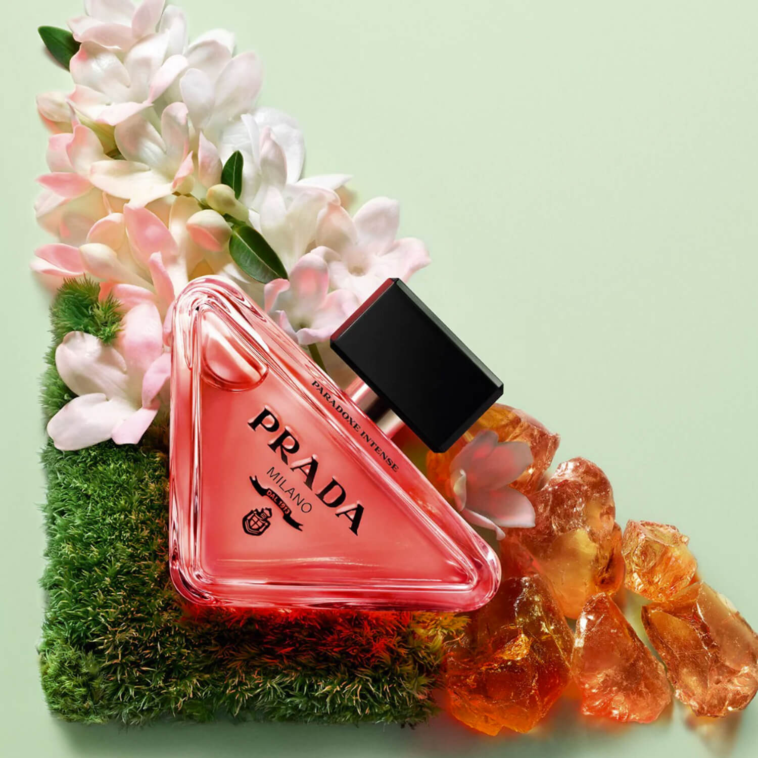 Prada perfume bottle with flowers and decorative elements on a light green background