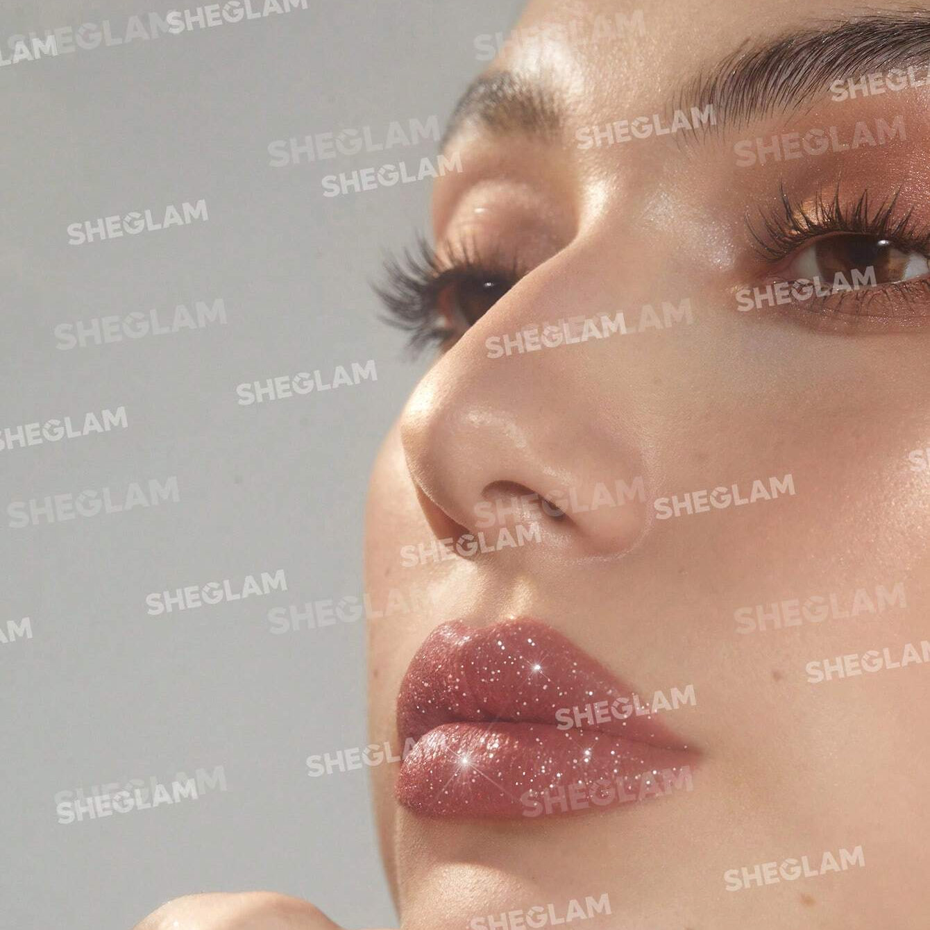 Close-up of a person wearing pink glittery lipstick with 'SHEGLAM' branding.