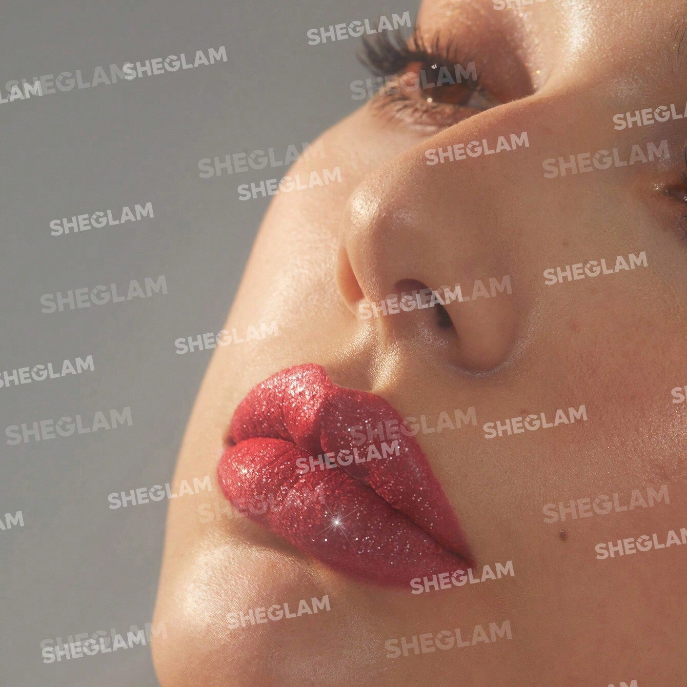 Close-up of a person's shoulder with red glittery product applied, branded 'SHEGLAM'.