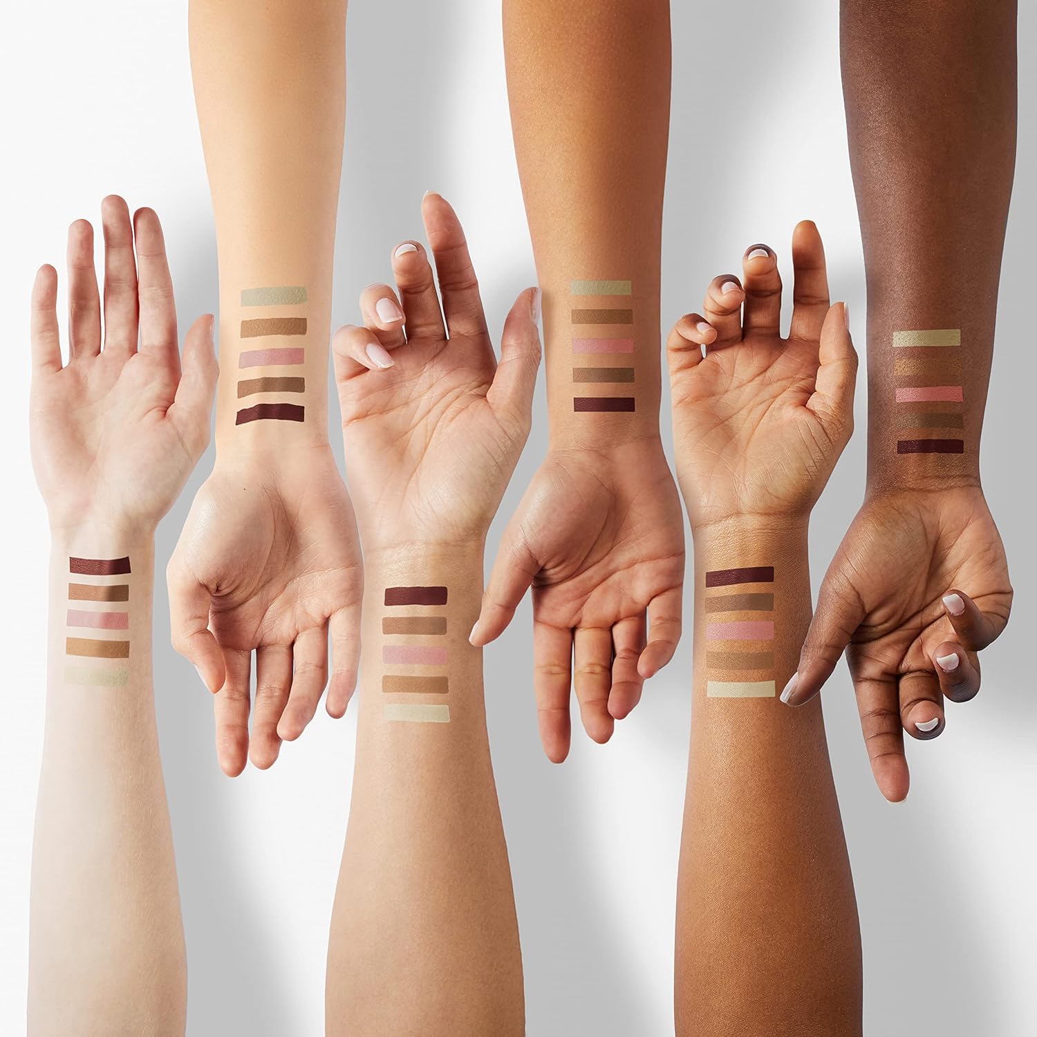 Multiple hands with different skin tones displaying makeup swatches on their wrists.